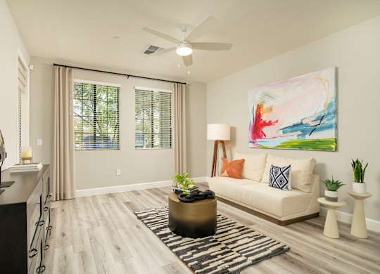 A living room with a large painting on the wall and a white couch.