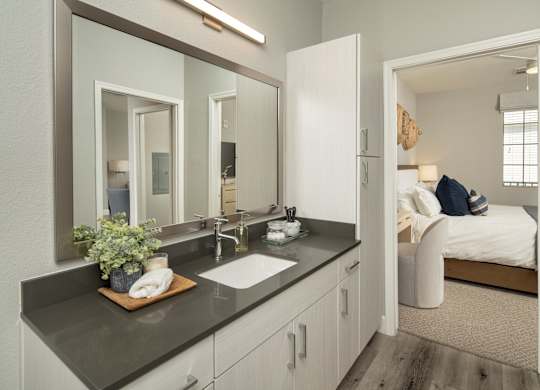 A bathroom with a double sink vanity and a mirror above it.