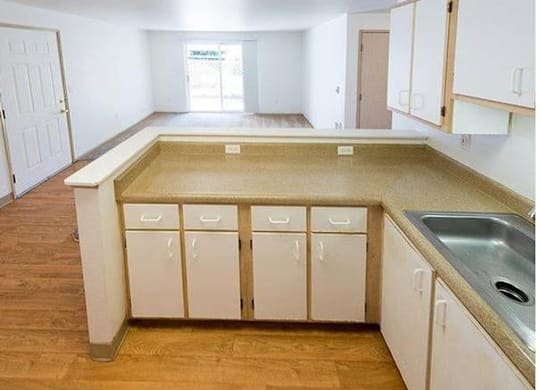 A kitchen with white cabinets and a wooden floor.