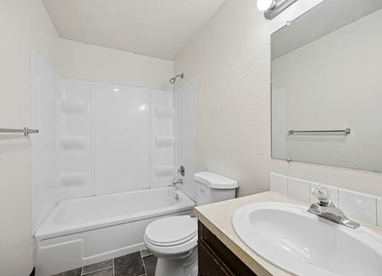 A white bathroom with a toilet, sink, and bathtub.