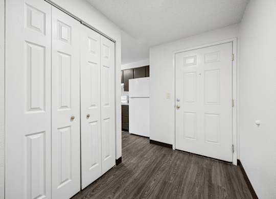 A hallway with white doors and a wooden floor.