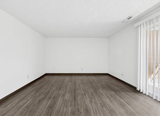 A room with wooden flooring and white walls.