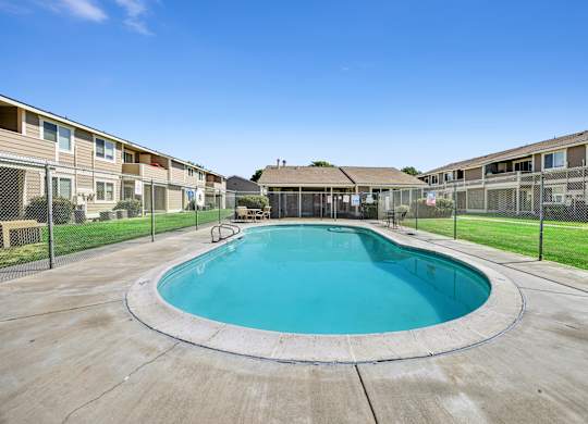 A round swimming pool in a residential area surrounded by a fence.