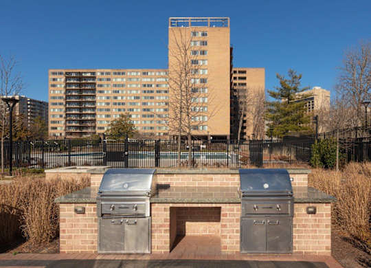 A brick structure with two ovens on top of it in front of a tall building.