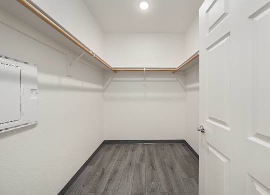 A white door is on the right side of a room with wood flooring.