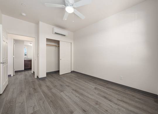 A room with a ceiling fan and wooden flooring.