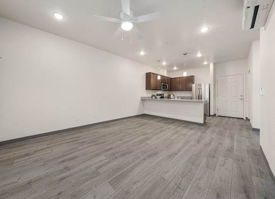 A spacious room with a ceiling fan and wooden flooring.