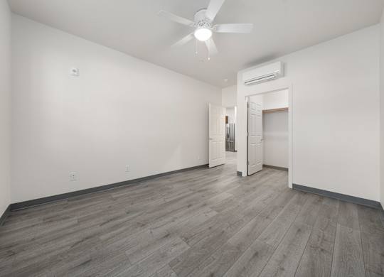 A room with a ceiling fan and a doorway leading to another room.