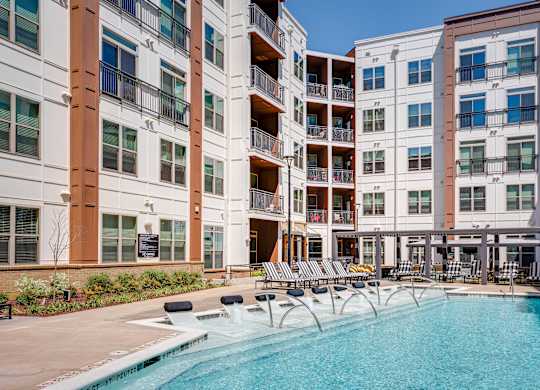 an outdoor swimming pool with chaise lounge chairs and a building in the background