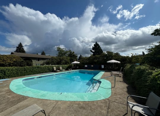 a pool with chairs and umbrellas and a cloudy sky