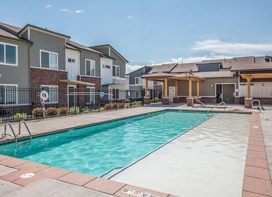 A swimming pool surrounded by a brick border and a fence with a sign that says "No Diving".