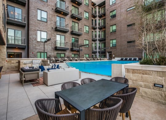 a patio with a table and chairs next to an apartment building