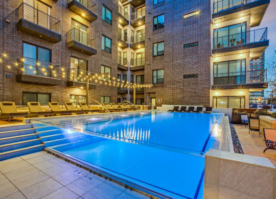 a pool with a blue water feature in front of an apartment building
