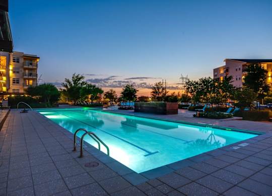 A swimming pool lit up with blue lights at dusk.