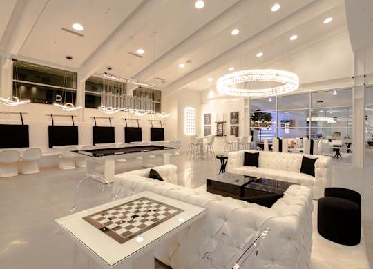 A modern living room with white furniture and a chessboard on the coffee table.
