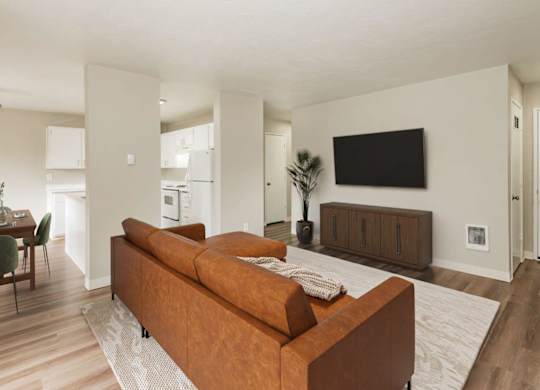A living room with a brown couch and a flat screen TV mounted on the wall.