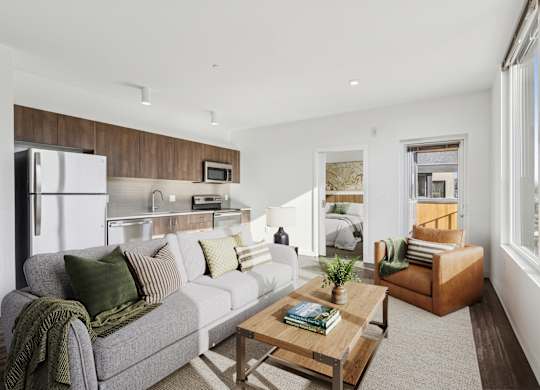 A modern living room with a grey couch, a wooden coffee table, and a large window.