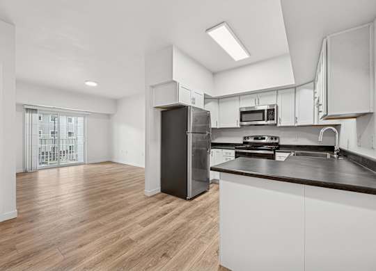 A kitchen with white cabinets and a black refrigerator.