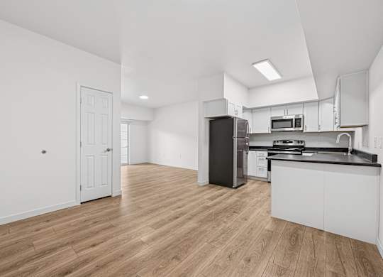 A kitchen with white cabinets and a black refrigerator.