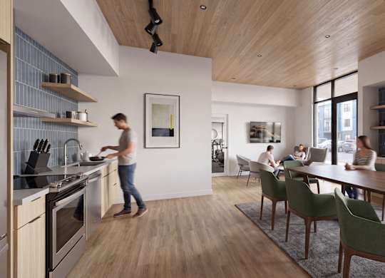 A woman is cooking in a modern kitchen with a wooden floor and ceiling.