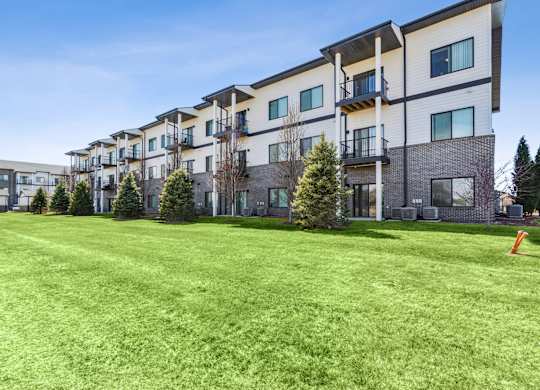 A row of modern apartment buildings with green lawns in front.