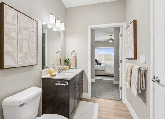 A bathroom with a toilet, sink, and mirror.