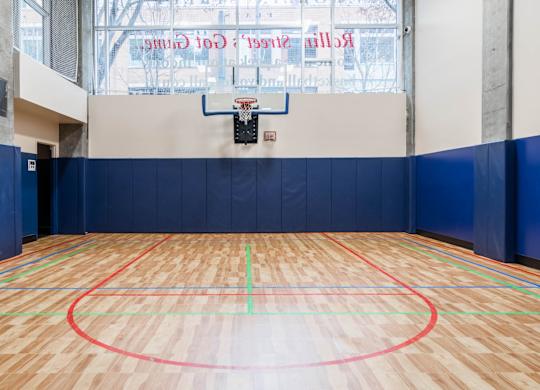 A basketball court with a wooden floor and a hoop mounted on the wall.