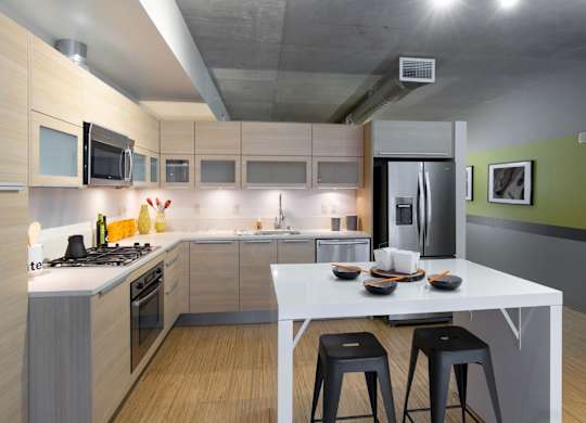 A modern kitchen with a white table and black stools.