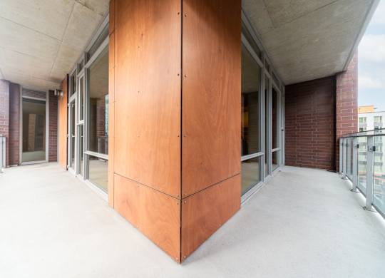 A long hallway with a brown wall on the side and a white ceiling.