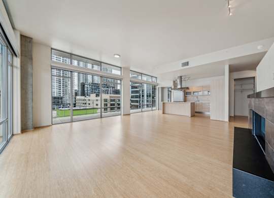 A spacious room with wooden floors and a kitchen area.