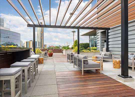 A patio with wooden floors and grey cushions.