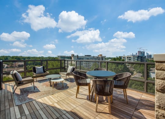 a patio with a round table and chairs on a wooden deck with a view of the city
