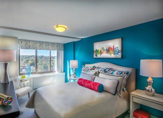 A bedroom with a large bed and a window overlooking a cityscape.