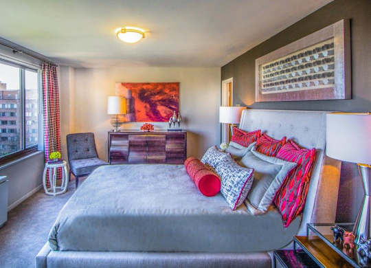 A bedroom with a large bed and a window overlooking a cityscape.