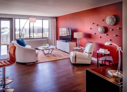 A living room with a red wall and a white chair.