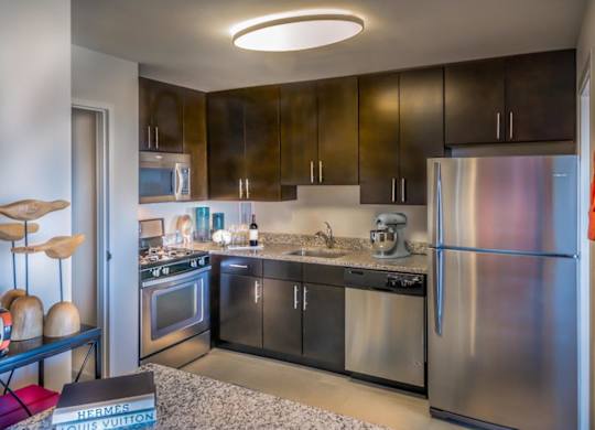A modern kitchen with a refrigerator, oven, and sink.