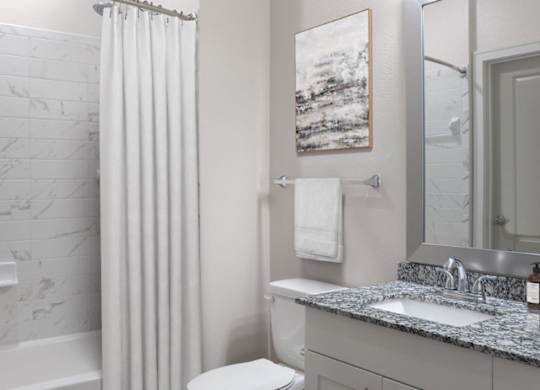 A bathroom with a marble tub and a white toilet.