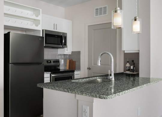 A kitchen with a black refrigerator and granite countertops.