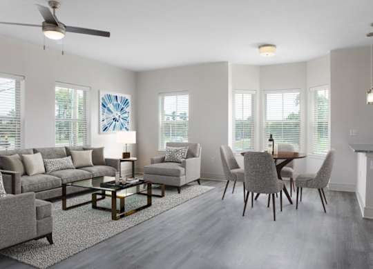 A living room with a grey couch, a glass coffee table, and a ceiling fan.