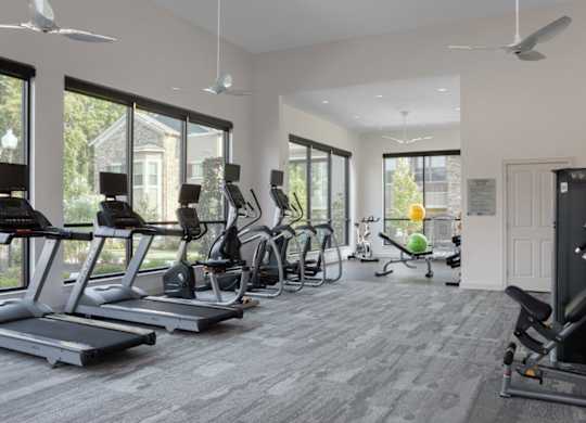 A spacious gym with treadmills, elliptical machines, and a weight rack.