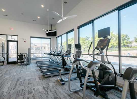 A gym with treadmills and a fan.