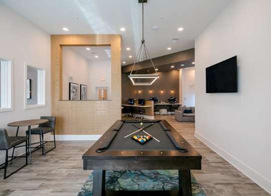 A billiard table is in the middle of a room with a chair and a mirror.