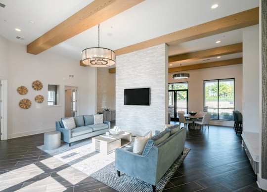 A modern living room with a grey couch and a white brick wall.