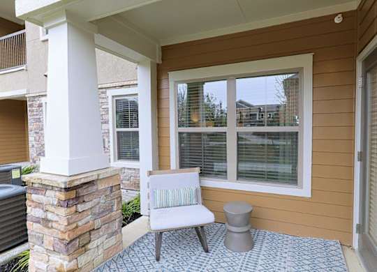 A patio with a white chair and a stone pillar.