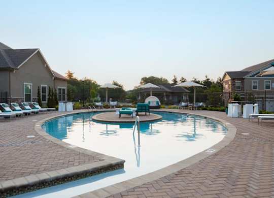 A large outdoor swimming pool surrounded by lounge chairs and umbrellas.