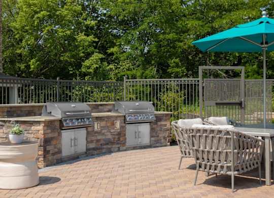 A patio with a table, chairs, and a grill.