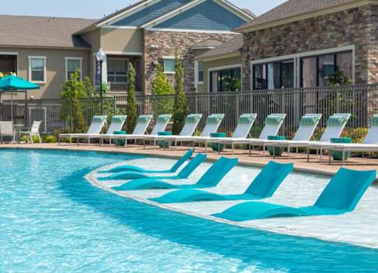 A row of blue lounge chairs are set up by a pool.