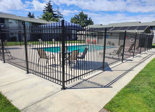 a wrought iron fence around a pool with patio furniture
