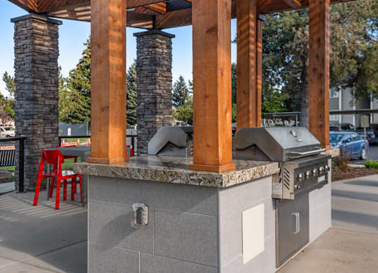 A modern outdoor kitchen with a grill and seating area.