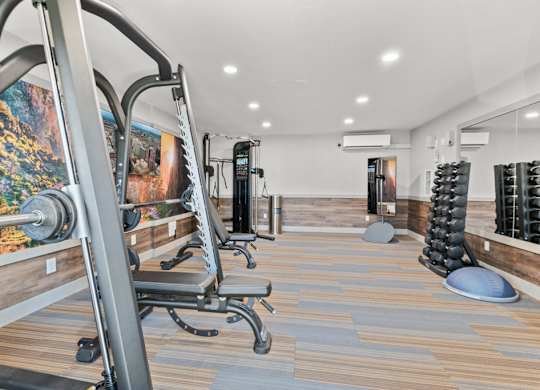 A gym with a row of exercise machines and a wooden floor.